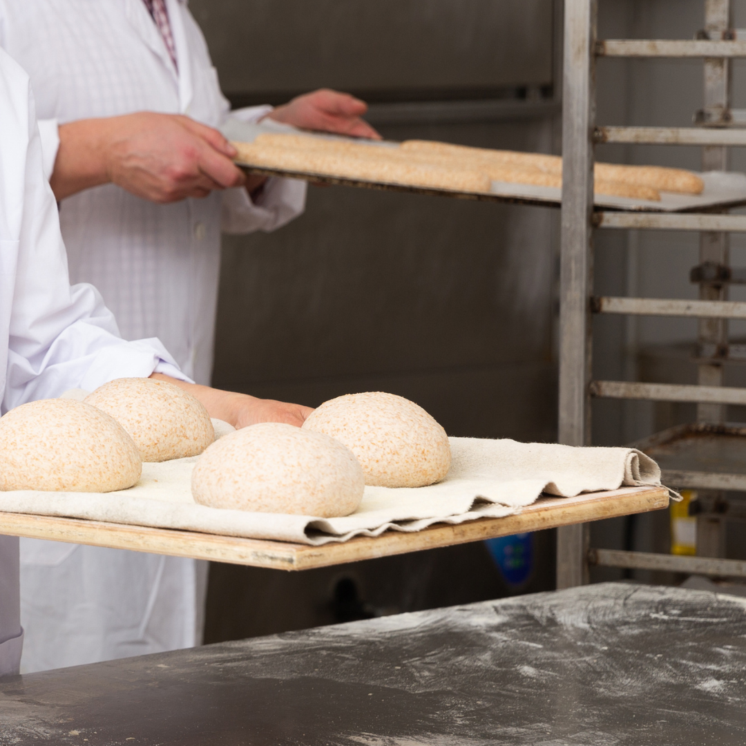 Dough on bakery trays going into racks by bakers reading for prooving