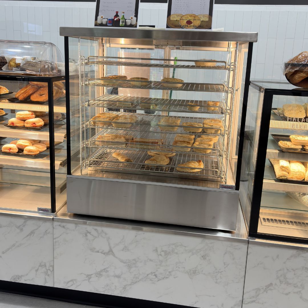 Bakery heated display case stainless steel and frameless glass with wire shelves and hot pies and pastries inside